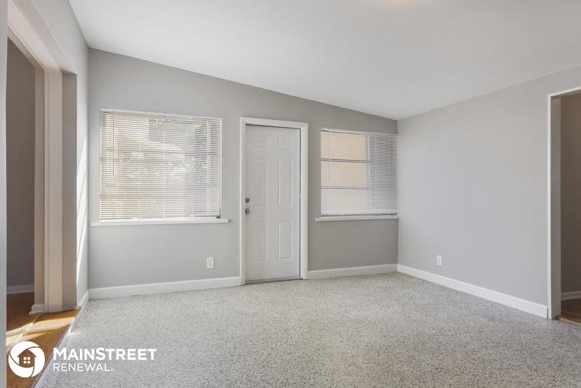 an empty room with a door and two windows