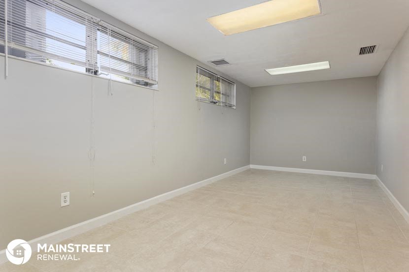 an empty living room with two windows and a ceiling light