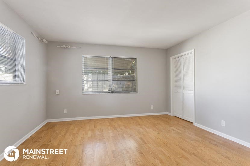 an empty living room with wood flooring and a window