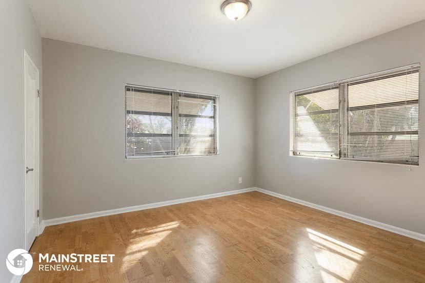 a living room with a wooden floor and two windows