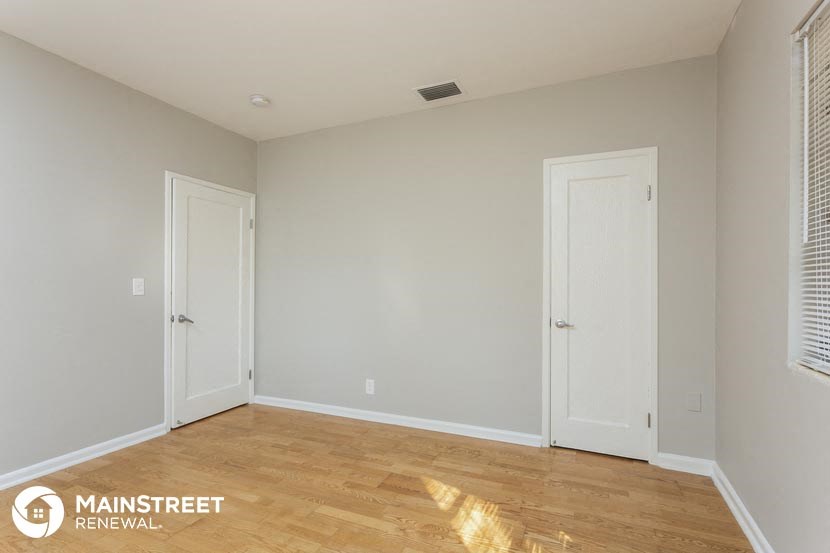 the living room of an apartment with a wooden floor and two doors