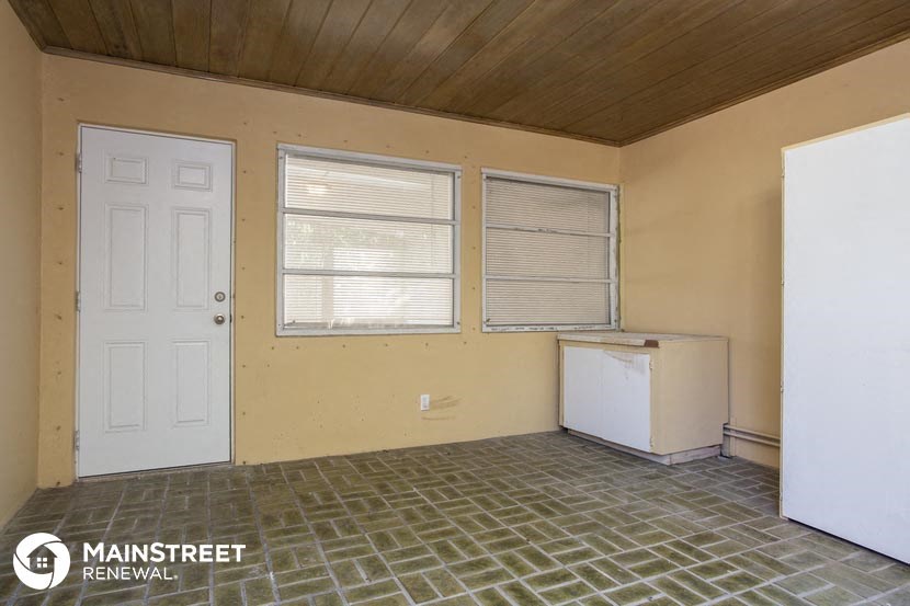 an empty room with a white door and two windows