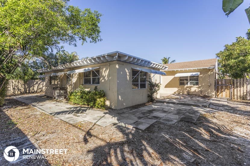 a small house with a driveway and a fence