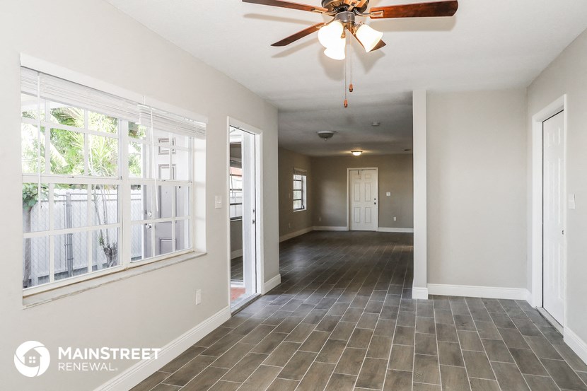 an empty living room with a ceiling fan and a large window