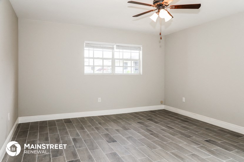 an empty room with a ceiling fan and a window