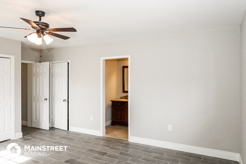 a living room with a ceiling fan and a door to a bathroom