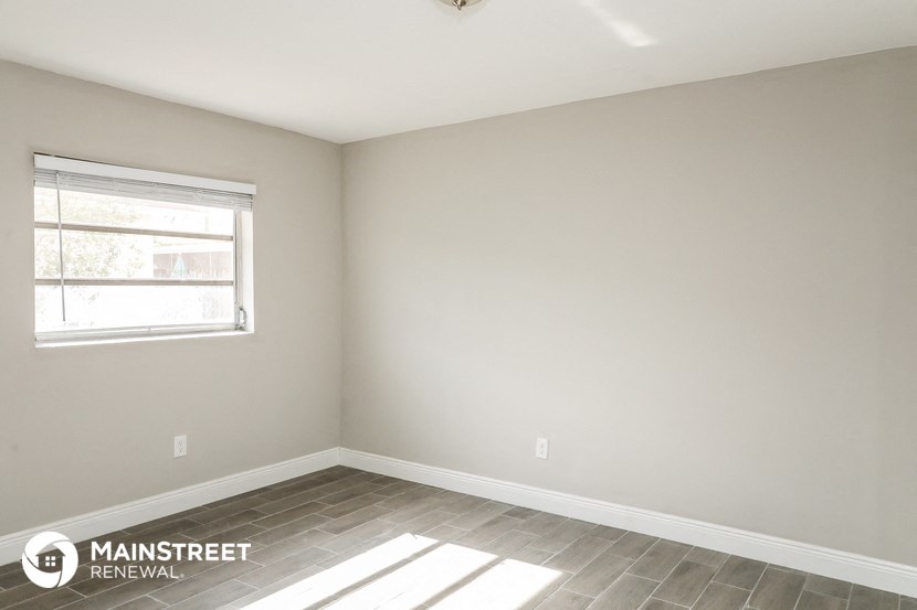 the corner of a room with a window and wood floors