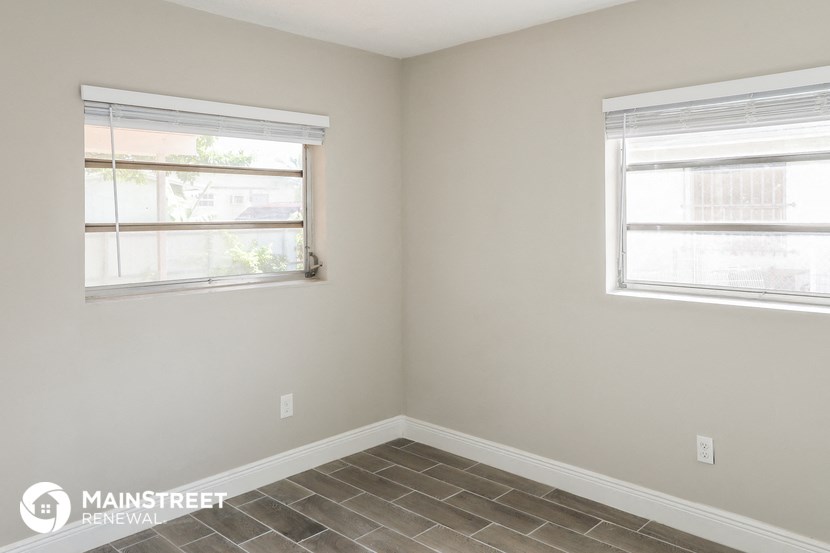a small room with two windows and a tiled floor