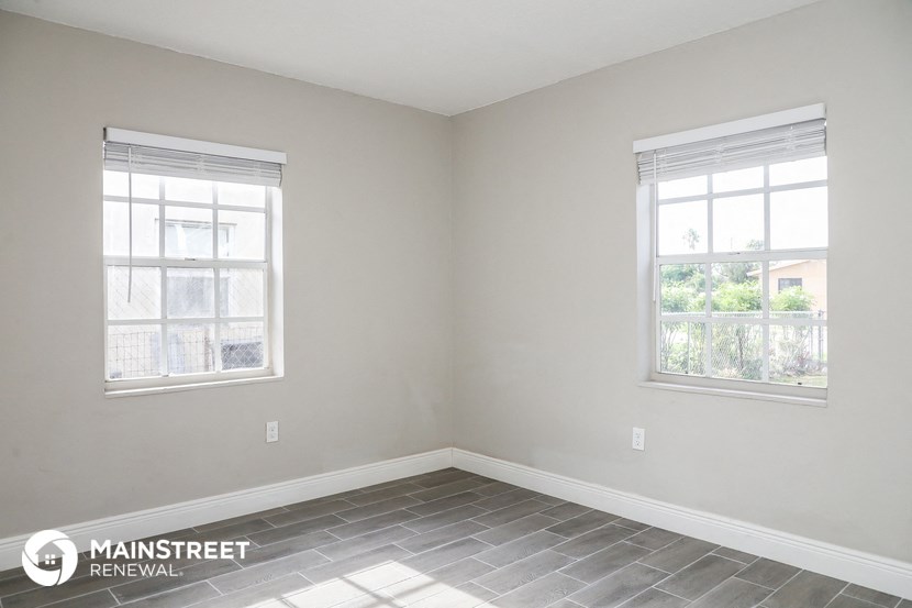a small room with two windows and a tiled floor