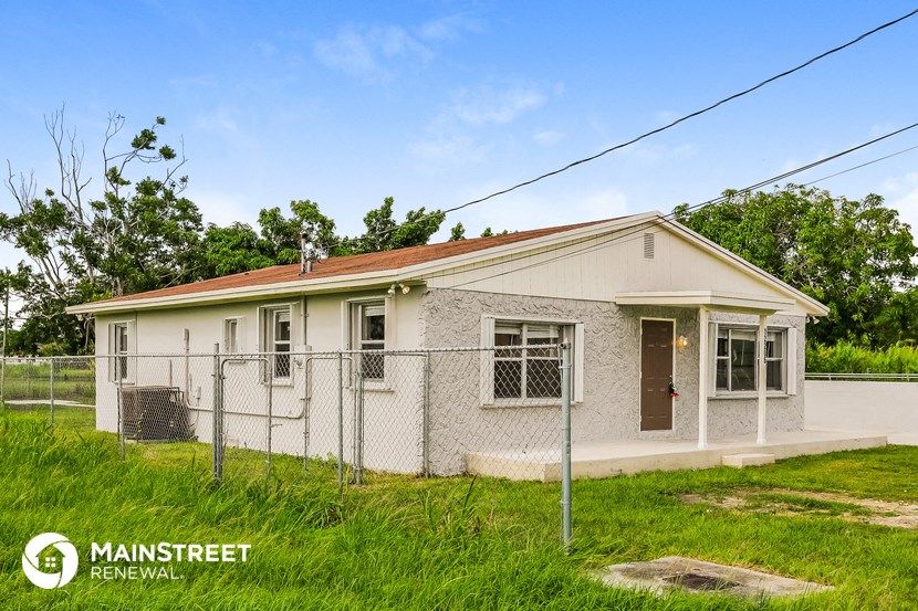 a small white house with a fence in front of it