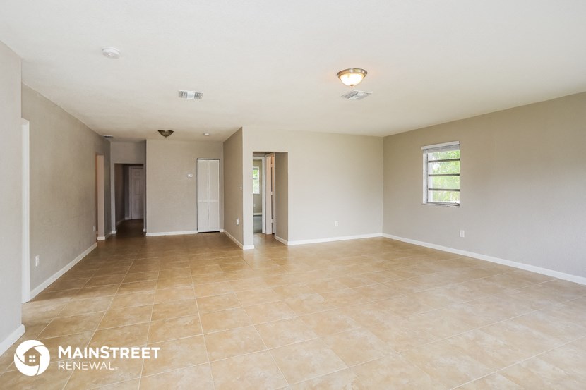 an empty living room with tile floors and white walls