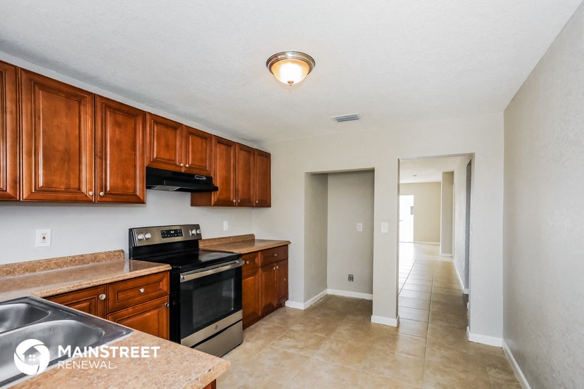a kitchen with wood cabinets and black appliances and a long hallway