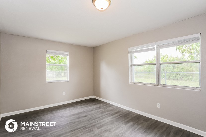 the living room of a home with wood flooring and two windows