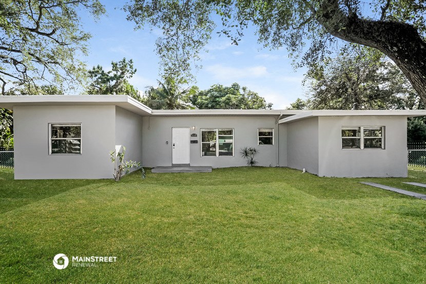 a white house with a lawn and a tree