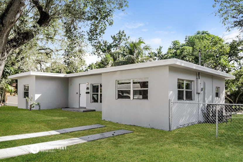 a small white house with a lawn and trees