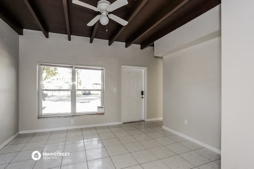an empty living room with a ceiling fan and a window