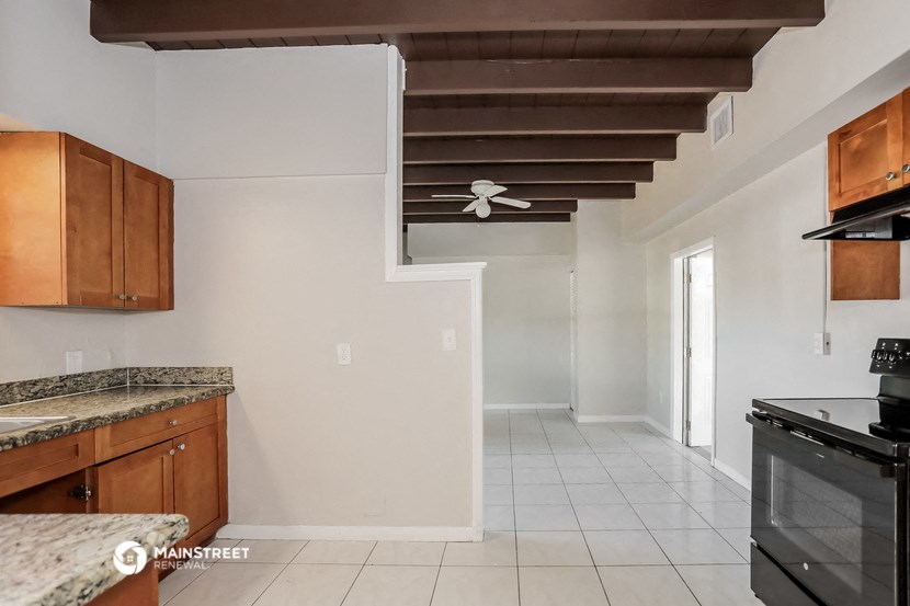 an empty kitchen with a stove and a ceiling fan
