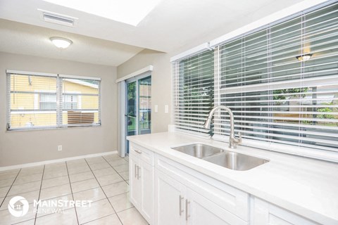 a white kitchen with a sink and a window