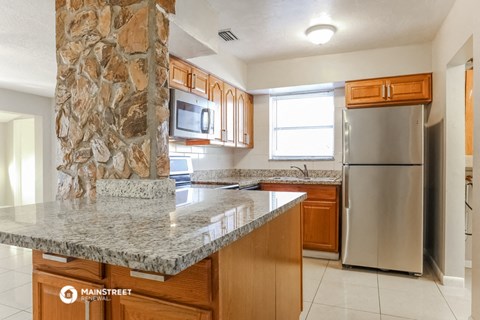 a kitchen with a granite counter top and a stainless steel refrigerator