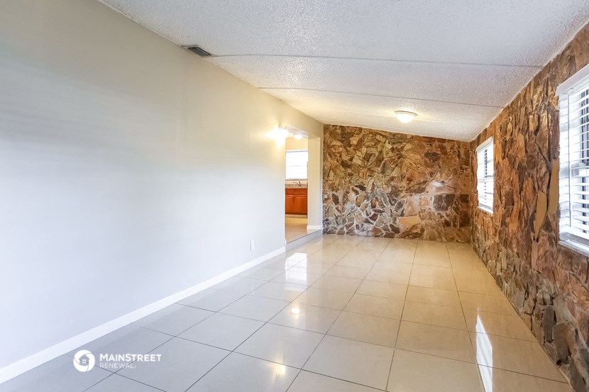 an empty living room with a stone wall and a tiled floor