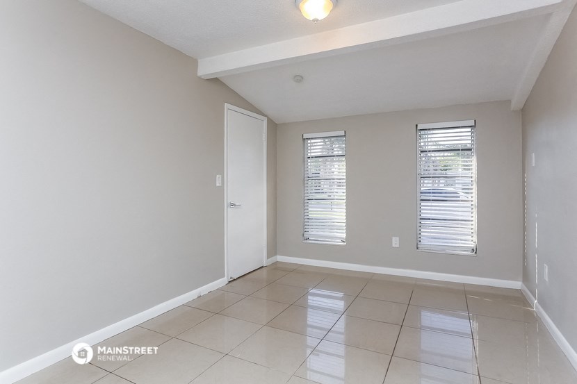 an empty living room with a door and two windows