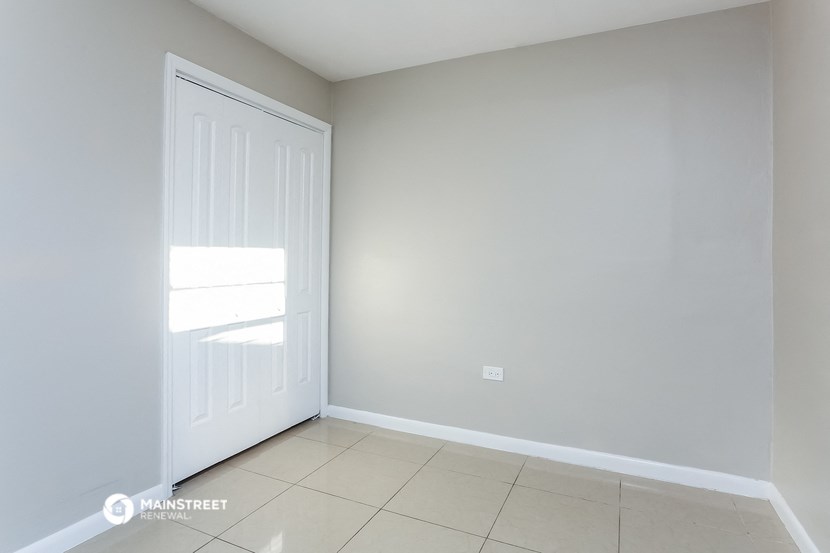 an empty room with a white door and a tiled floor