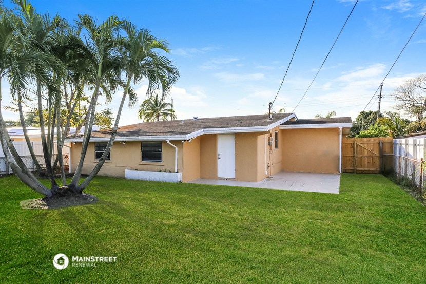 a small yellow house with a palm tree in the yard