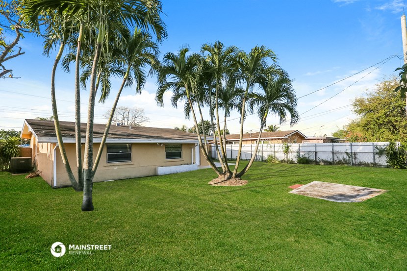 a backyard with palm trees and a house
