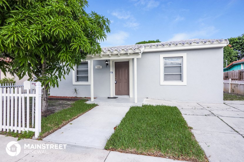 a small white house with a yard and a white fence
