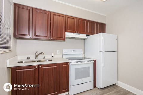 a kitchen with white appliances and wooden cabinets and a refrigerator