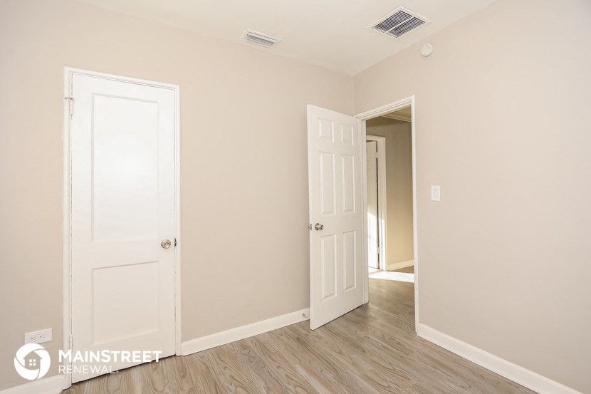 a bedroom with two doors and a door to a hallway