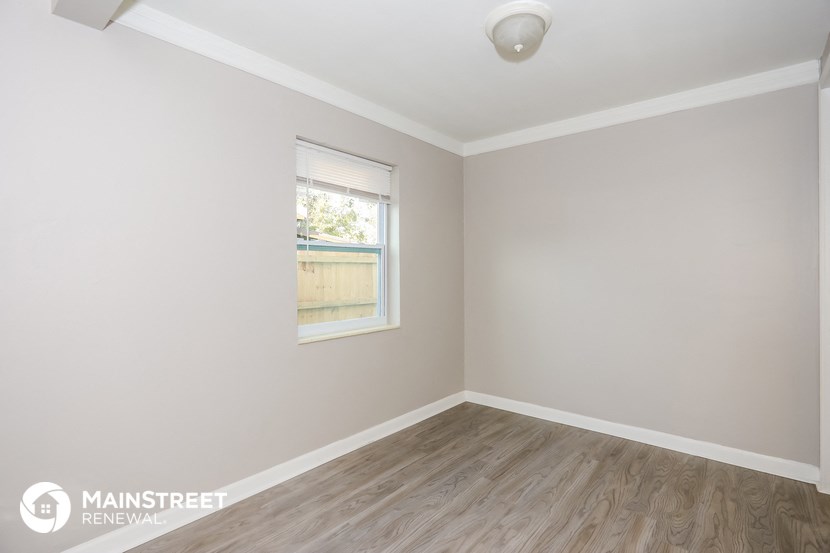 the interior of a white room with wooden floors and a window