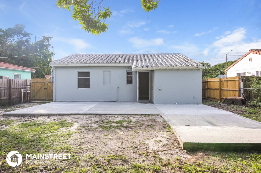 a small white house with a driveway and a fence