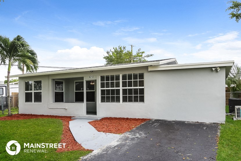 the front of a white house with a driveway and grass
