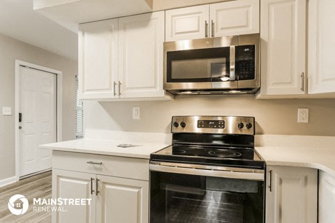 a kitchen with white cabinets and a stove and a microwave