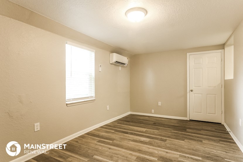 the interior of a bedroom with wood flooring and a white door