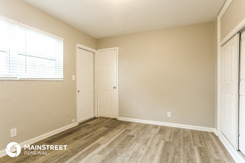the living room of an apartment with wood flooring and a window