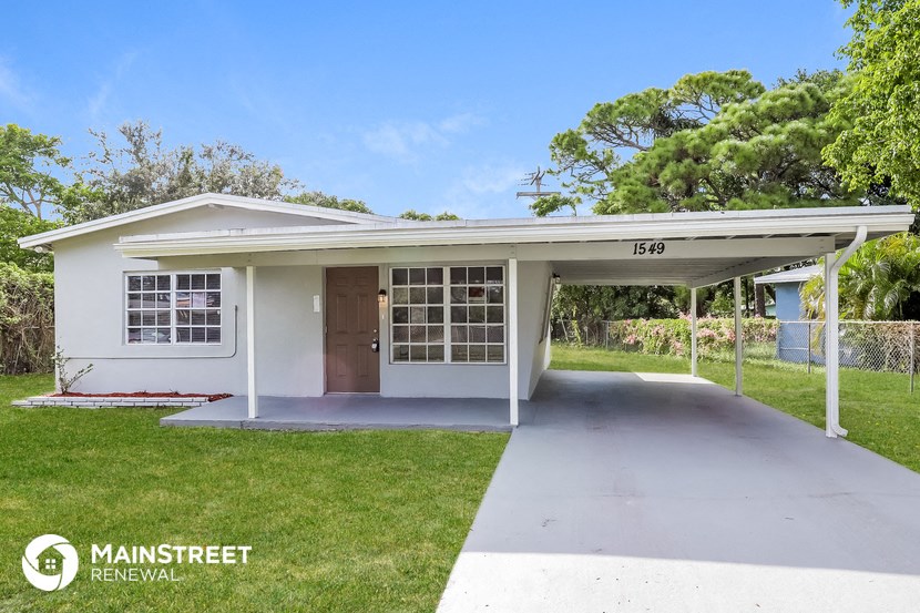 a small white house with a driveway and a covered porch