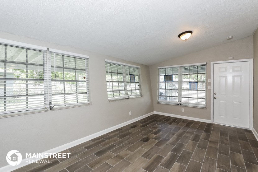 the living room of a home with a white door and windows