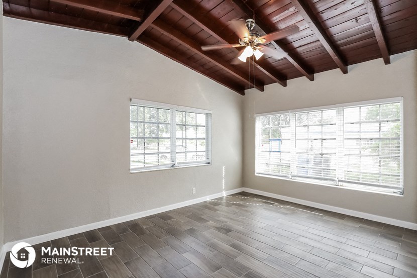 the spacious living room with wood floors and a ceiling fan