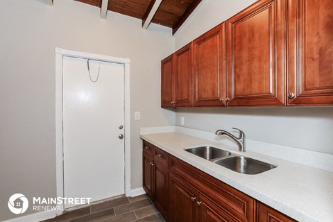 a kitchen with a sink and wooden cabinets and a white door