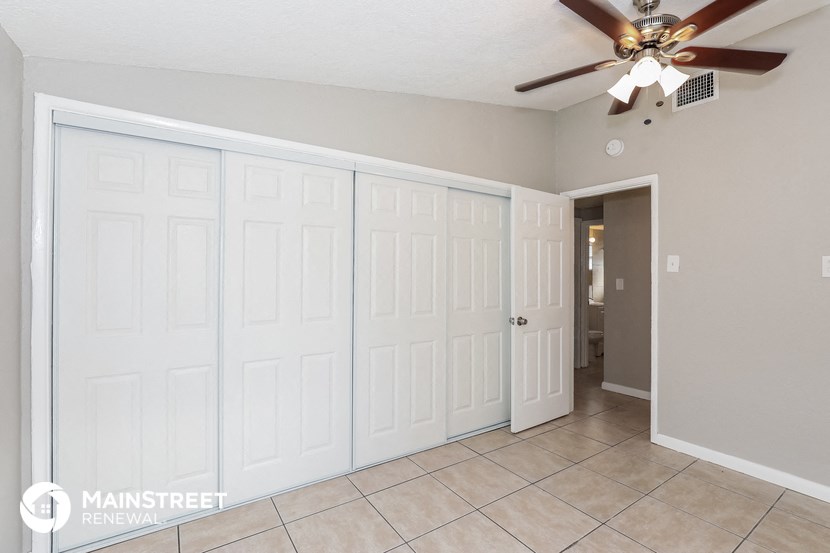 the living room has two closets and a ceiling fan