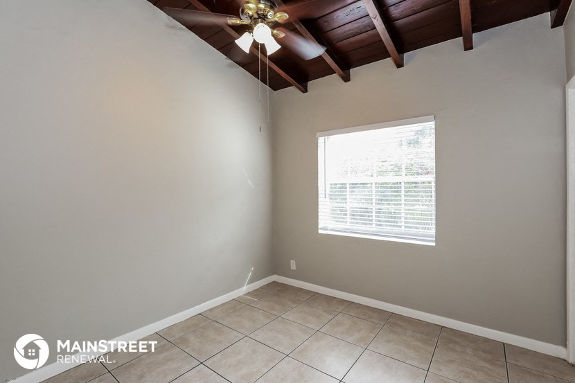 the living room of an empty room with a ceiling fan and a window