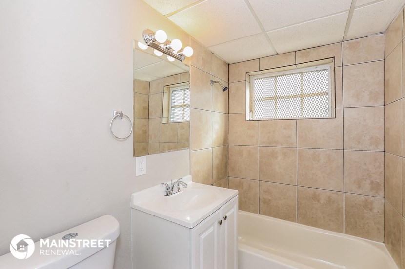 a white bathroom with a tub and a sink and a mirror