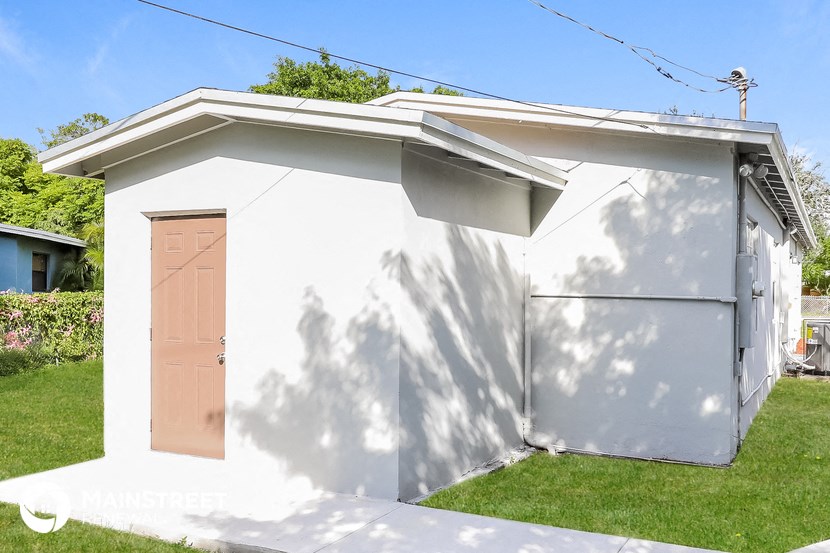 a small white shed with a door on the side of it
