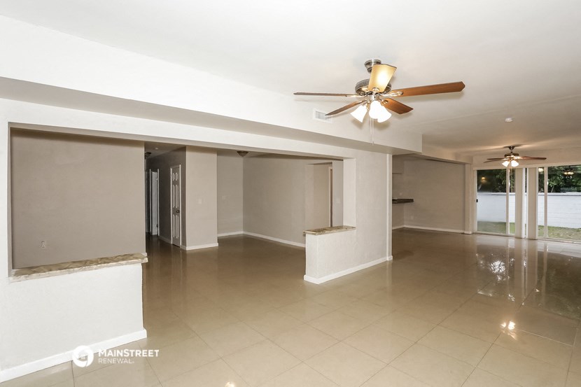 an empty living room with a ceiling fan
