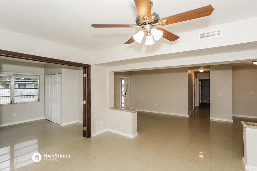 an empty living room with a ceiling fan