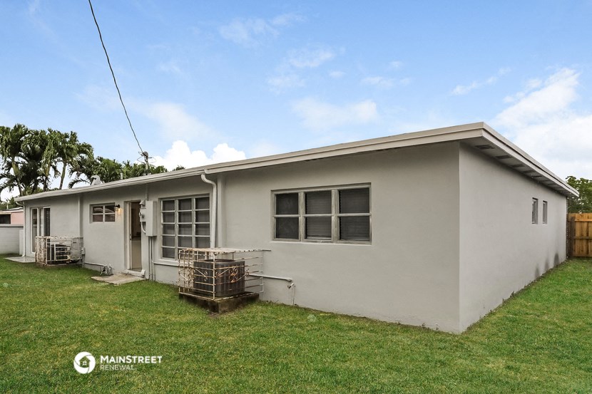 a small white house with a lawn and a fence