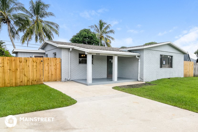 a white house with a wooden fence and a driveway