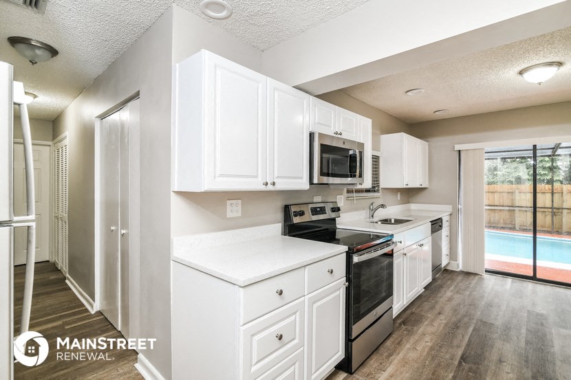 a kitchen with white cabinets and black appliances and a window